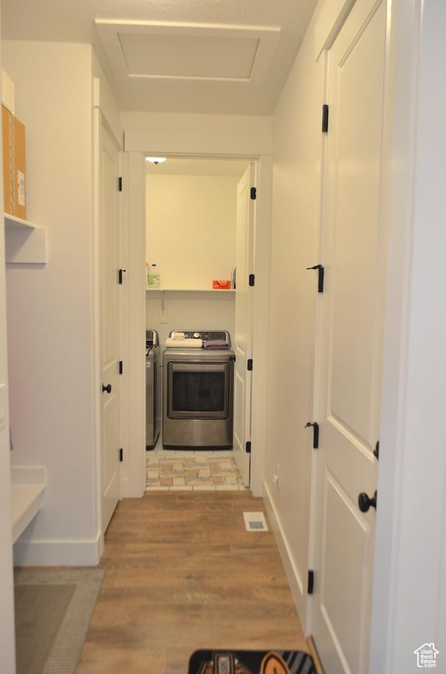 clothes washing area with washer and dryer, visible vents, light wood-style flooring, and attic access