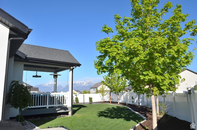 view of yard with a deck with mountain view and a fenced backyard