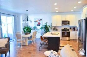 kitchen featuring white cabinets, a notable chandelier, a sink, light countertops, and stainless steel appliances