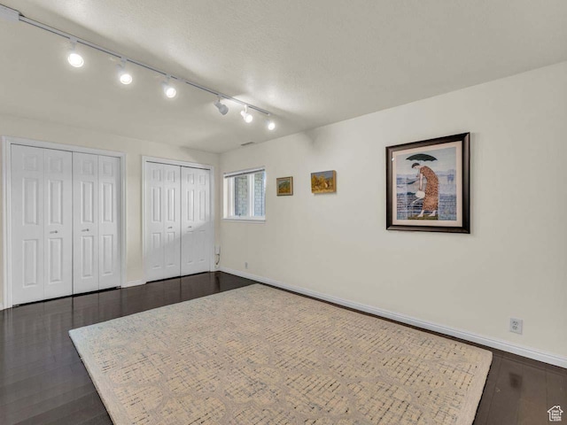 799 Northpoint Ct, Salt Lake City, UT 84103 - unfurnished bedroom with two closets, dark wood-style floors, rail lighting, and a textured ceiling