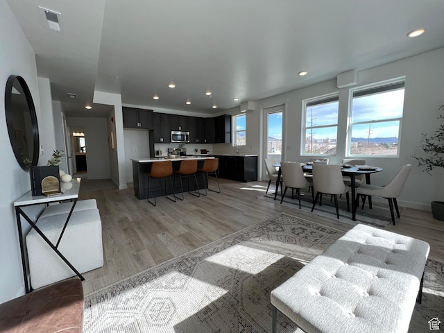 living area featuring recessed lighting, baseboards, visible vents, and light wood-style floors