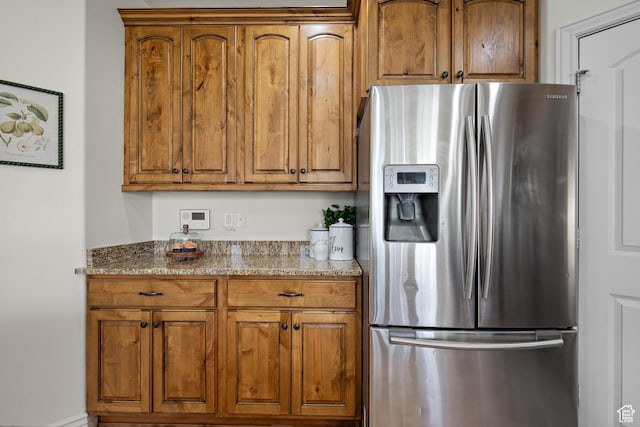 927 S Iris Ln W, Mapleton, UT 84664 - kitchen with brown cabinetry, light stone counters, and stainless steel fridge with ice dispenser
