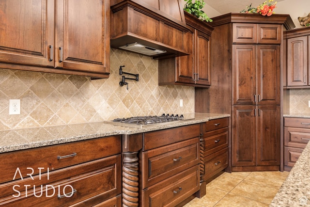 415 W Silver Hills Rd, Leeds, UT 84746 - kitchen featuring stainless steel gas cooktop, light tile patterned floors, light stone counters, custom exhaust hood, and decorative backsplash