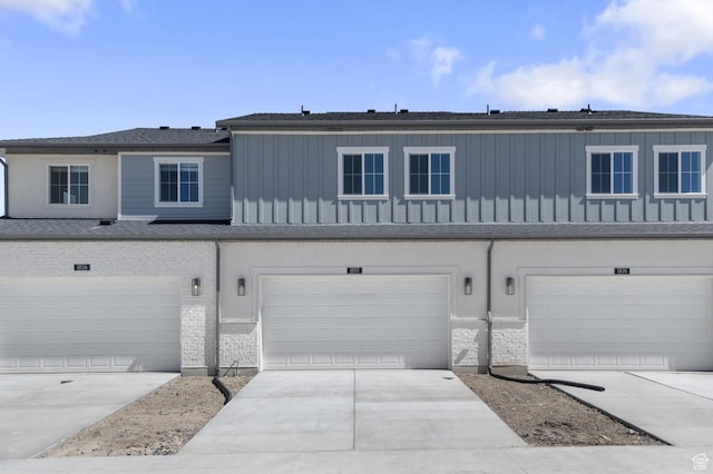 multi unit property featuring board and batten siding, an attached garage, and driveway