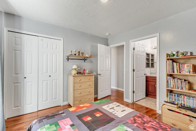 5943 N Genoa Ln W, Stansbury Park, UT 84074 - bedroom with baseboards, a closet, light wood-type flooring, and a textured ceiling