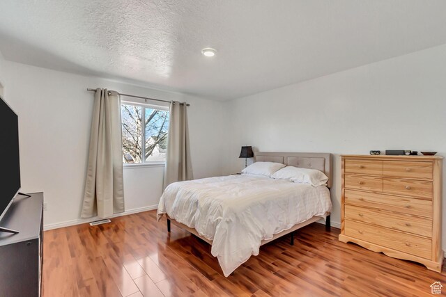 5943 N Genoa Ln W, Stansbury Park, UT 84074 - bedroom featuring baseboards, a textured ceiling, light wood-style flooring, and visible vents