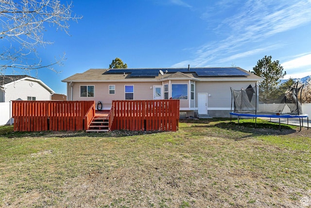 5943 N Genoa Ln W, Stansbury Park, UT 84074 - rear view of property featuring roof mounted solar panels, a trampoline, a yard, and a deck