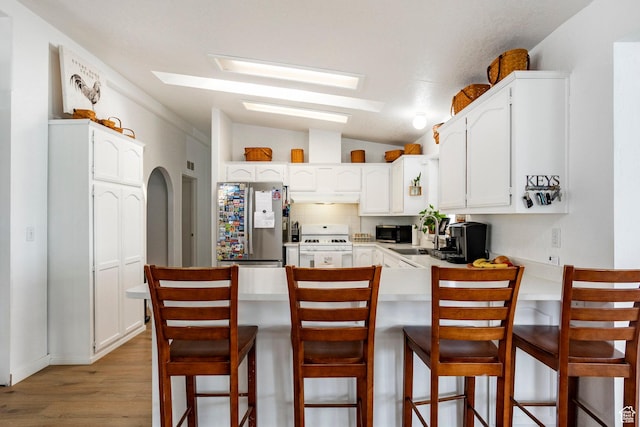 24517 W Rock Creek Rd, Duchesne, UT 84021 - kitchen featuring vaulted ceiling with skylight, white gas stove, freestanding refrigerator, a peninsula, and light wood-style flooring