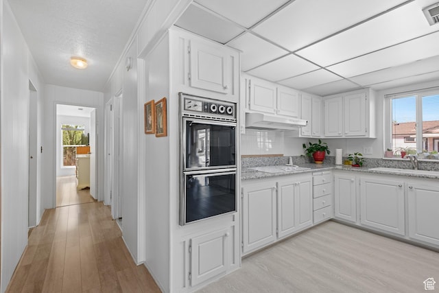 1526 N Dixie Downs Dr Unit 53, St George, UT 84770 - kitchen with white cabinets, a sink, double oven, light wood-style flooring, and under cabinet range hood