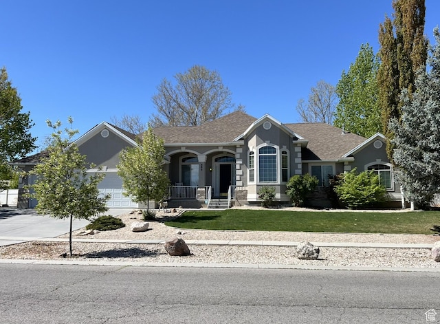 986 Davenport Dr S, Grantsville, UT 84029 - view of front of home with covered porch, an attached garage, a shingled roof, concrete driveway, and a front lawn