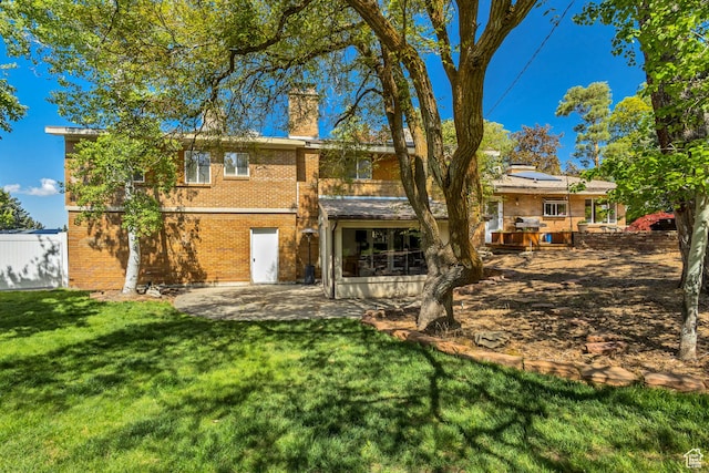 1253 Oakridge Ln, Bountiful, UT 84010 - back of house featuring brick siding, a patio, a lawn, solar panels, and a chimney