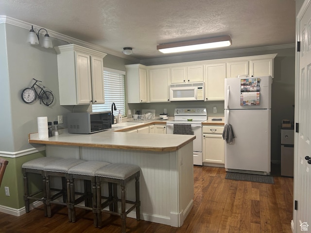 325 W 650 N Unit 11, Orem, UT 84057 - kitchen featuring a sink, a peninsula, dark wood-style floors, white appliances, and white cabinetry