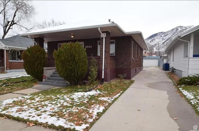 bungalow-style home featuring an outbuilding, central AC unit, a detached garage, brick siding, and a mountain view