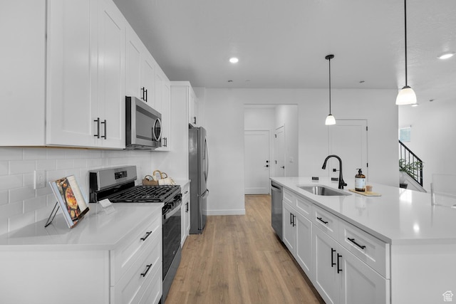 kitchen featuring backsplash, a center island with sink, a sink, white cabinets, and stainless steel appliances