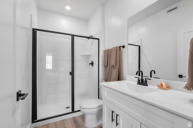 bathroom featuring vanity, a stall shower, toilet, and wood finished floors