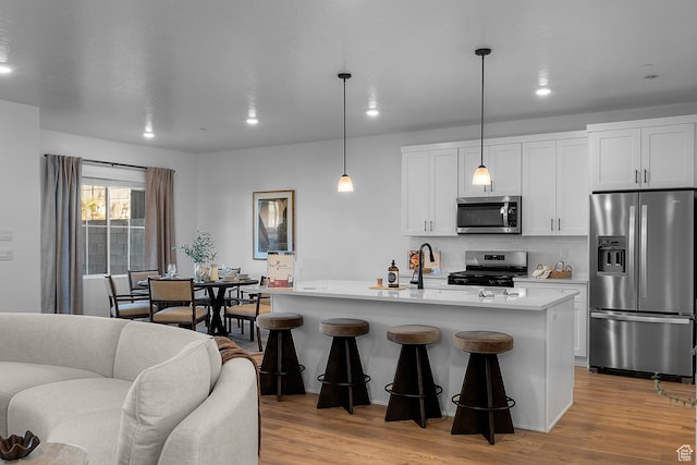 kitchen featuring white cabinets, appliances with stainless steel finishes, light wood-style floors, light countertops, and backsplash