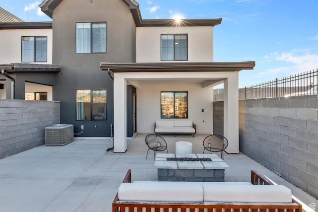 rear view of house with an outdoor living space with a fire pit, a patio, stucco siding, and fence private yard