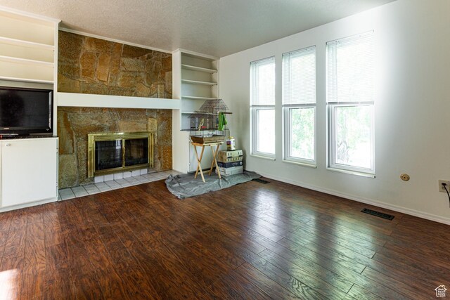 5952 S 2550 W, Roy, UT 84067 - unfurnished living room featuring hardwood / wood-style floors, a stone fireplace, baseboards, a textured ceiling, and built in shelves