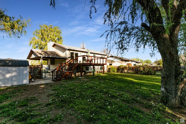 5952 S 2550 W, Roy, UT 84067 - rear view of house with an outdoor structure, a wooden deck, stairs, a storage unit, and a lawn
