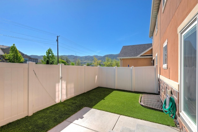 view of yard with a mountain view, a fenced backyard, and a patio area