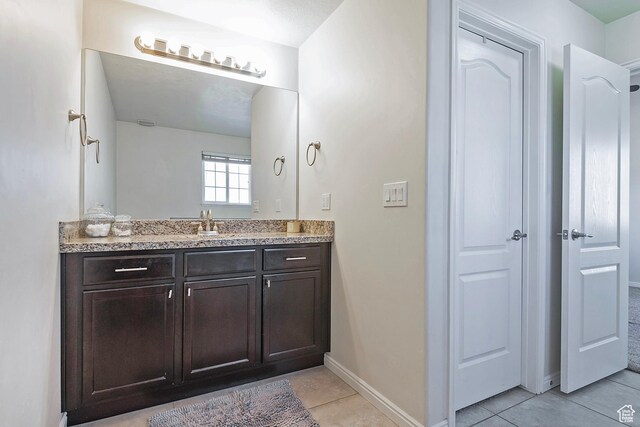 bathroom with tile patterned flooring, baseboards, and vanity