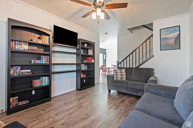 living area with ceiling fan, crown molding, wood finished floors, stairway, and baseboards