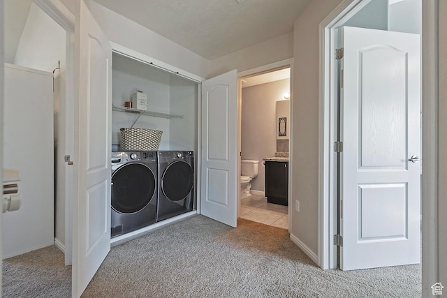 washroom featuring laundry area, baseboards, washing machine and dryer, and light colored carpet