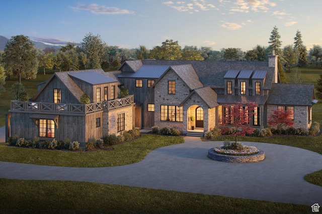 view of front of property with a standing seam roof, a chimney, metal roof, a lawn, and stone siding