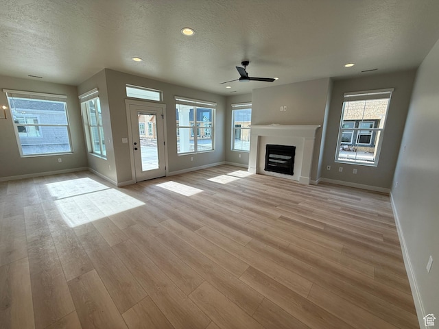 20 N 3830 W Unit 445, West Point, UT 84015 - unfurnished living room featuring ceiling fan, baseboards, light wood-style flooring, a fireplace, and a textured ceiling