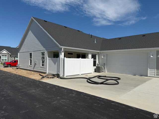 20 N 3830 W Unit 445, West Point, UT 84015 - rear view of property featuring driveway, an attached garage, a shingled roof, and cooling unit