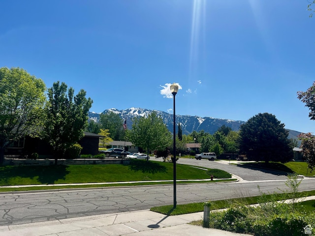 9968 S Blossom Dr, Sandy, UT 84092 - view of asphalt street with sidewalks, a mountain view, and street lights