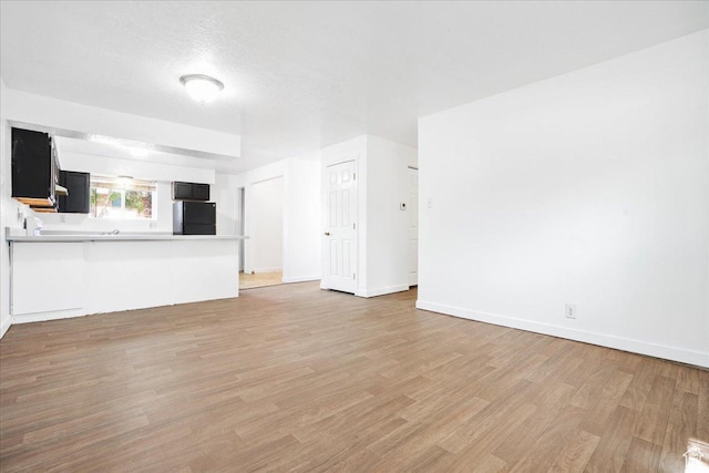 218 E Julie Anna Dr, Sandy, UT 84070 - unfurnished living room featuring baseboards and light wood-style flooring