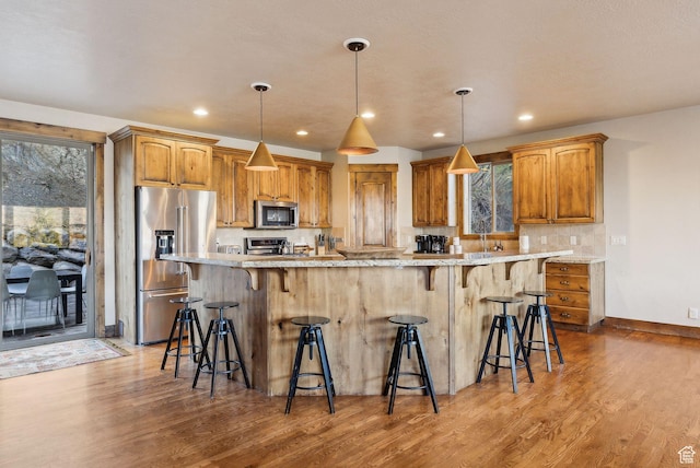 210 Parkview Dr, Summit Park, UT 84098 - kitchen with decorative backsplash, a kitchen bar, decorative light fixtures, wood finished floors, and stainless steel appliances