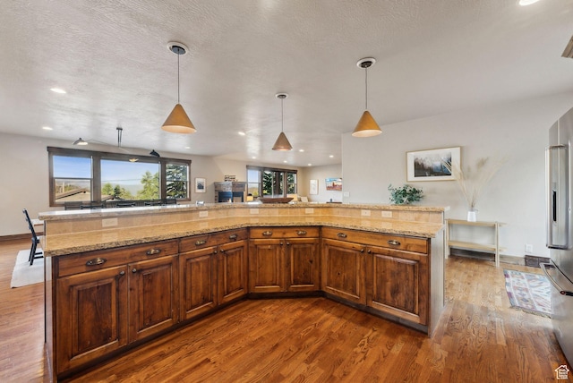 210 Parkview Dr, Summit Park, UT 84098 - kitchen featuring dark wood-type flooring, brown cabinets, decorative light fixtures, and light stone countertops