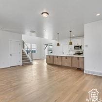kitchen with open floor plan, light wood-style flooring, decorative light fixtures, and light countertops