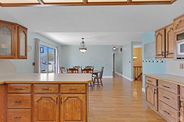 2137 W 550 N, West Point, UT 84015 - kitchen with light countertops, brown cabinets, a peninsula, and light wood-style flooring