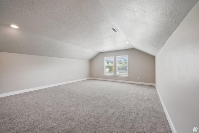 bonus room featuring carpet flooring, a textured ceiling, baseboards, lofted ceiling, and visible vents