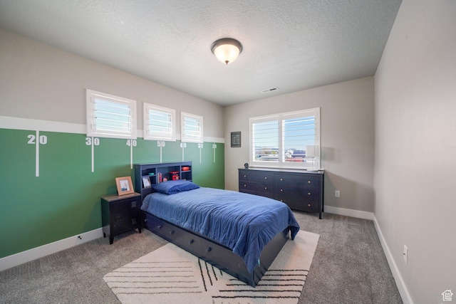 carpeted bedroom featuring a textured ceiling, baseboards, and visible vents