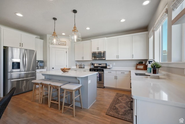 kitchen with a breakfast bar area, a kitchen island, light countertops, stainless steel appliances, and light wood-style flooring
