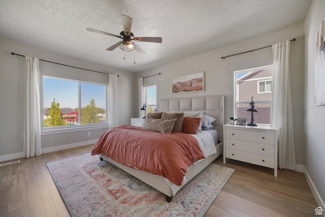 bedroom with light wood-style floors, baseboards, and a textured ceiling