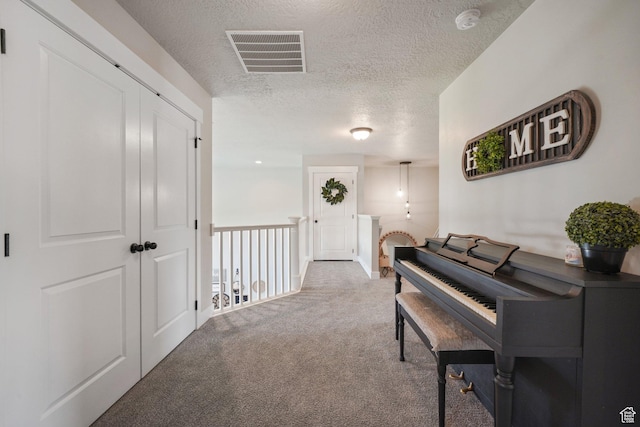 corridor featuring carpet floors, a textured ceiling, and visible vents