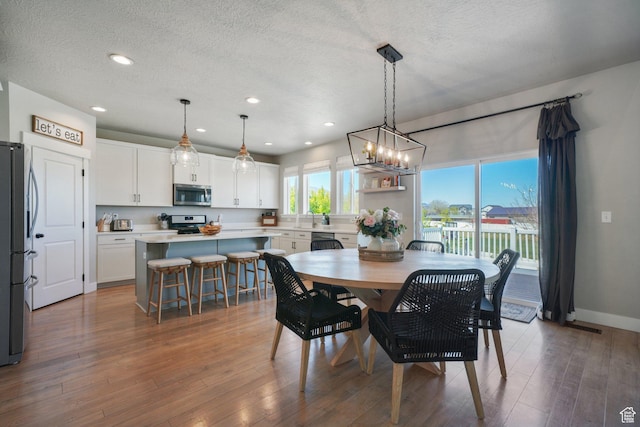 dining room featuring an inviting chandelier, wood finished floors, baseboards, recessed lighting, and a textured ceiling
