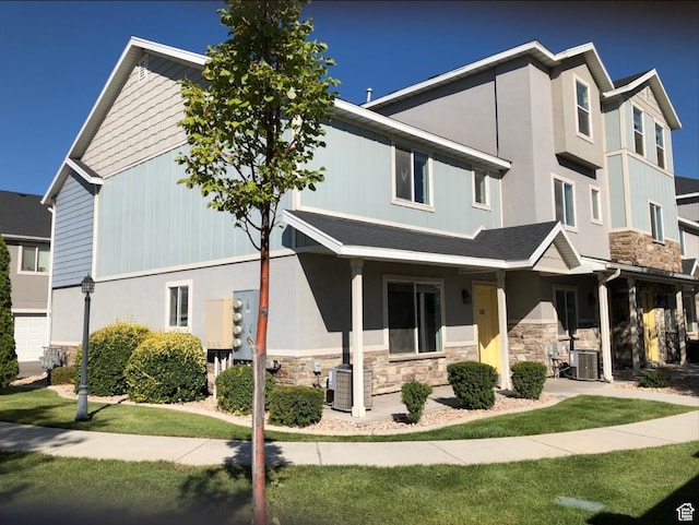view of property featuring a front yard, stone siding, and cooling unit