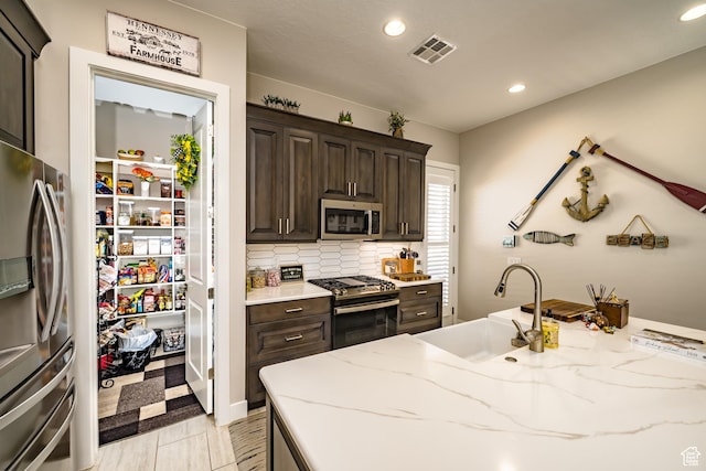 kitchen featuring visible vents, appliances with stainless steel finishes, dark brown cabinets, a sink, and recessed lighting