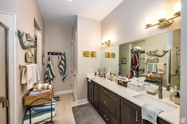 full bathroom with double vanity, a shower stall, and a sink