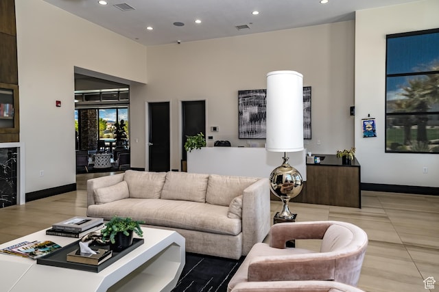 living room featuring a towering ceiling, baseboards, recessed lighting, and visible vents