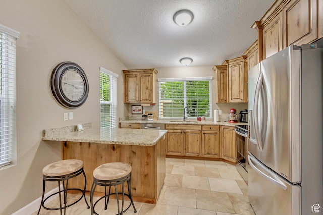 1155 S 2880 E, Spanish Fork, UT 84660 - kitchen with a kitchen bar, a textured ceiling, appliances with stainless steel finishes, a sink, and a peninsula