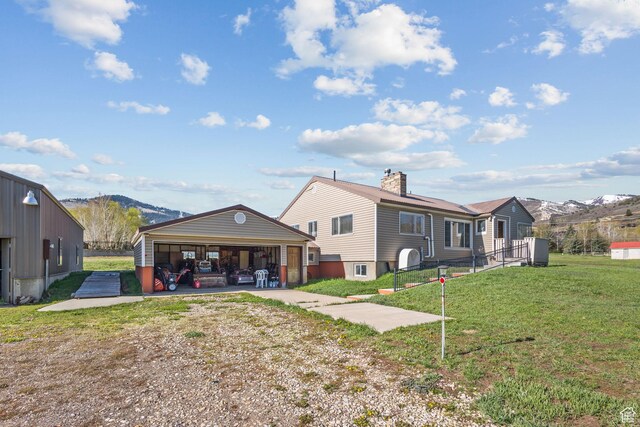 1745 Old Ranch Rd, Park City, UT 84098 - rear view of property with an outdoor structure, a chimney, a lawn, a mountain view, and driveway
