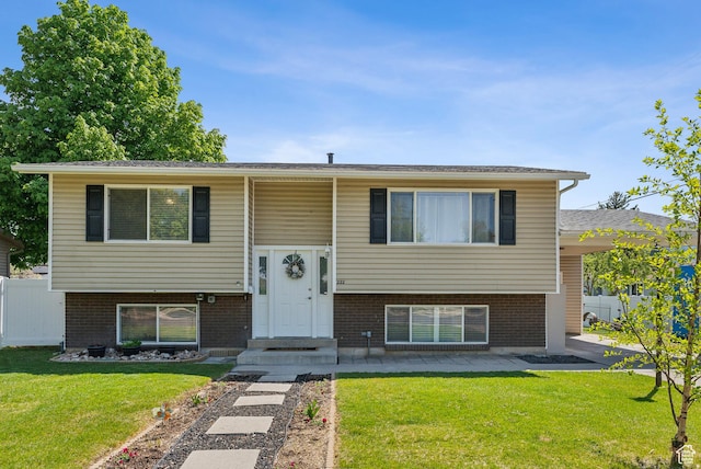 split foyer home with fence, a front lawn, and brick siding
