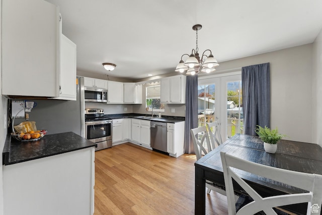 222 N 600th St E, Orem, UT 84097 - kitchen with dark countertops, a chandelier, white cabinets, a sink, and appliances with stainless steel finishes